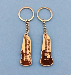 Ein Foto der personalisierten Akustik- und E-Gitarren-Schlüsselanhänger mit individuellem Namen auf blauem Hintergrund.